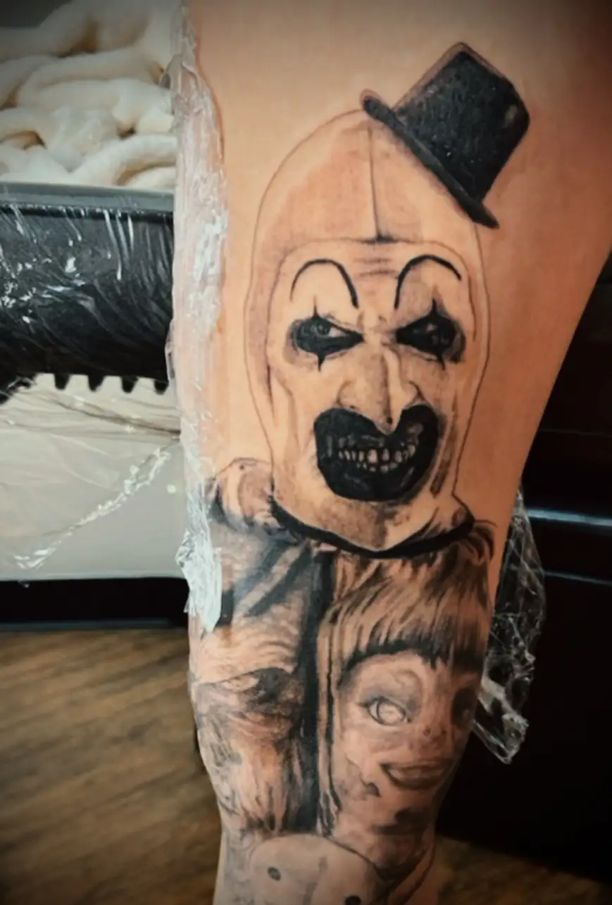 BL-ink Tattoo Colorado Springs horror piece: black-and-grey Art-the-Clown portrait with eerie doll below