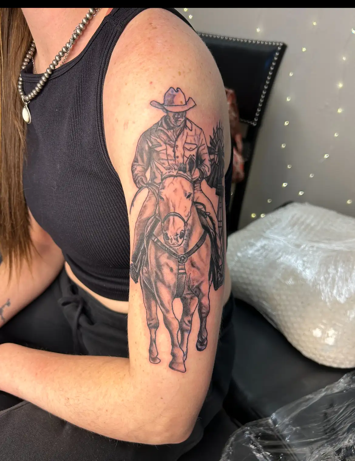 BL-ink Tattoo Colorado Springs upper-arm piece: black-grey cowboy riding a horse in classic western style