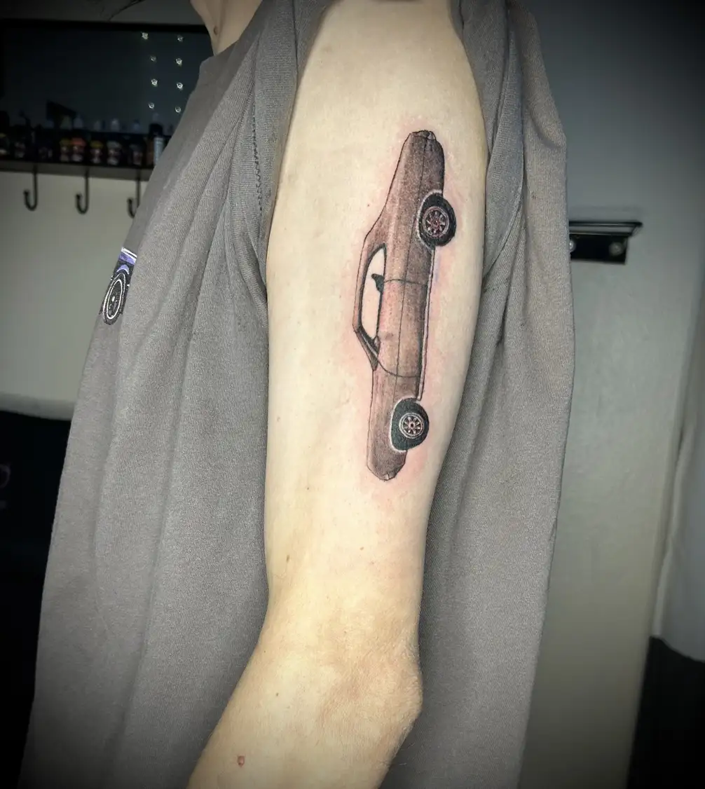 BL-ink Tattoo Colorado Springs upper-arm tattoo: minimalist side profile of a classic 1971 Ford Torino rendered in fine-line black and muted red shading.